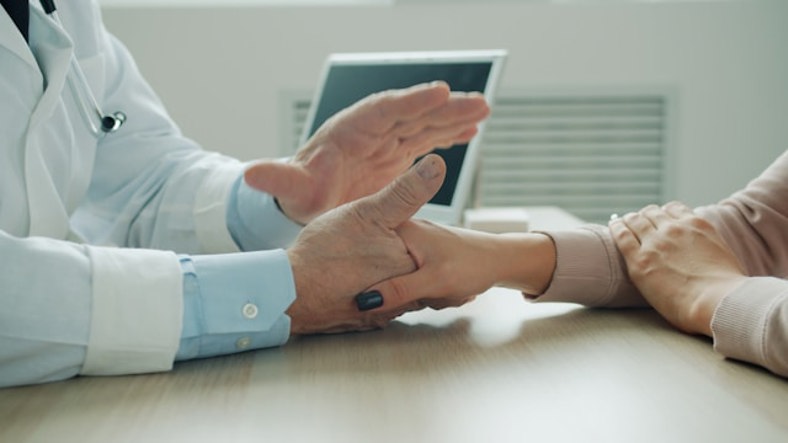 Patient and doctor discussing while holding hands